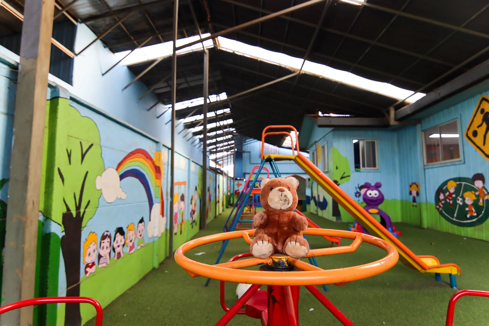 Juegos infantiles en el patio techado, con murales en las paredes